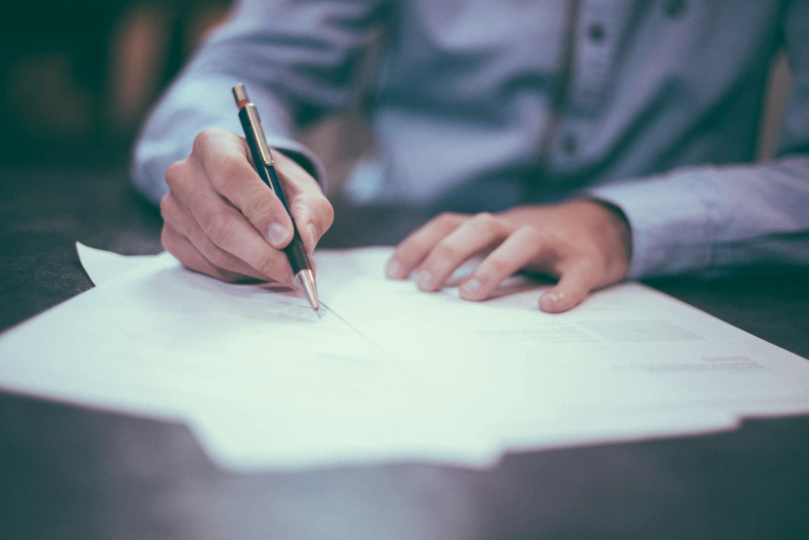 Hands signing a legal document with a pen