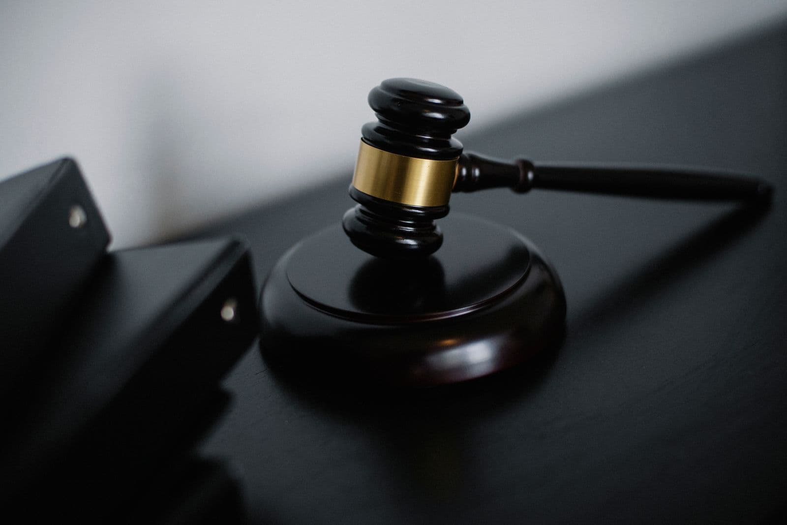 Wooden gavel with a brass band beside a black case file