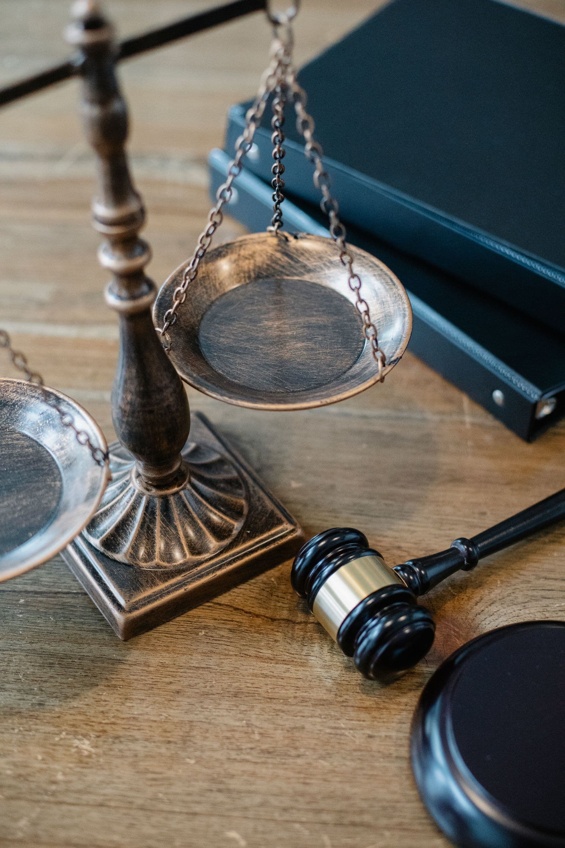 Brass scales of justice, a gavel, and a legal binder on a desk